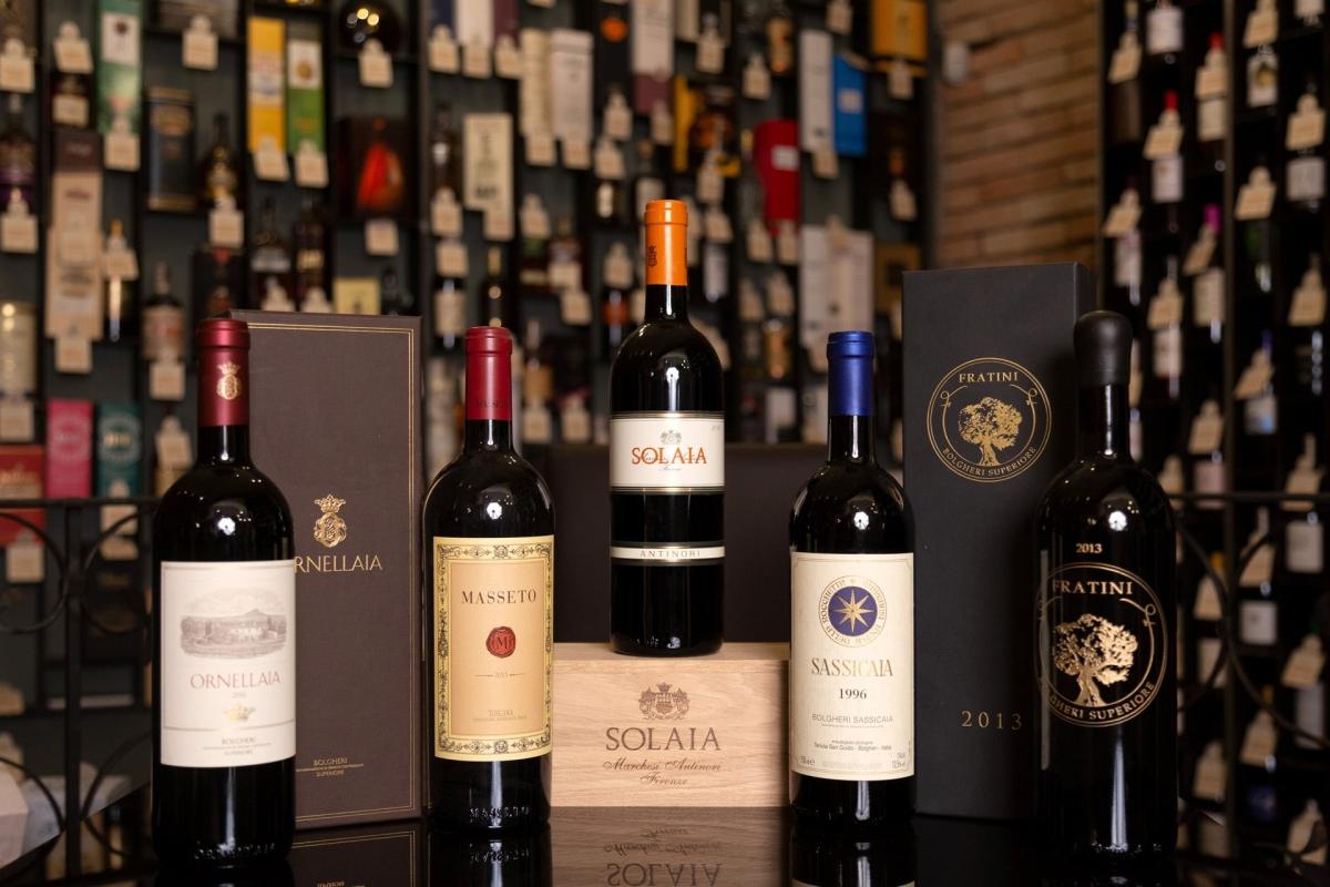 Ornellaia, Masseto, Solaia, Sassicaia e Fratini allineate davanti alla parete delle etichette