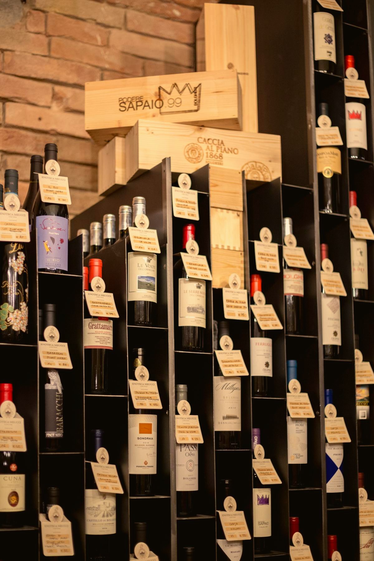 La parete delle bottiglie dell’enoteca, coi cartellini scritti a mano