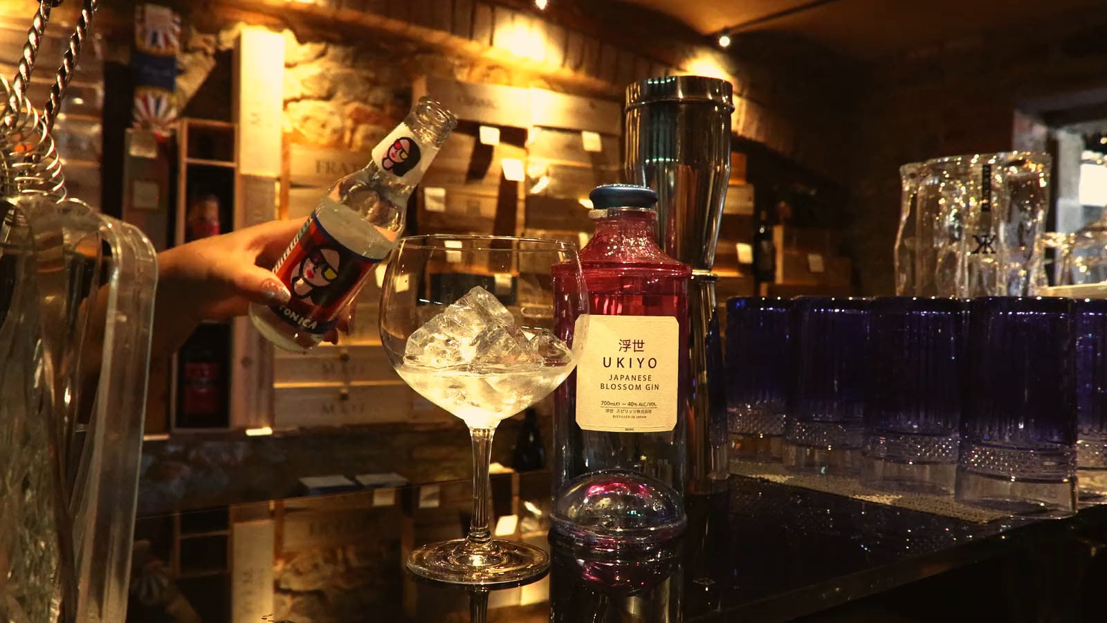 Un gin tonic che si riempie sul ghiaccio, nella luce calda della sala di pietra